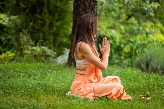 Woman practicing meditation in peaceful garden setting during spiritual journeys