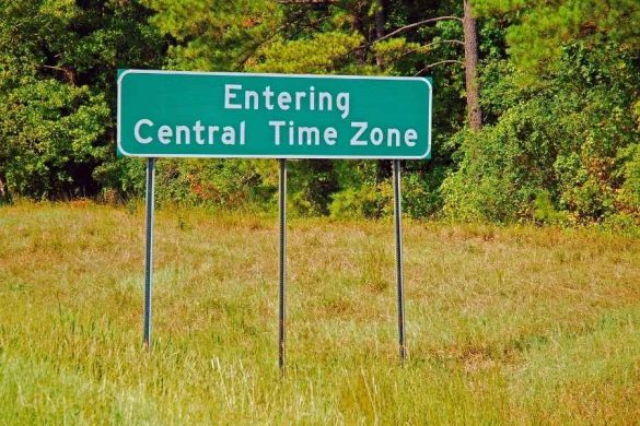 Time zone travelers road sign entering Central Time Zone surrounded by lush forest